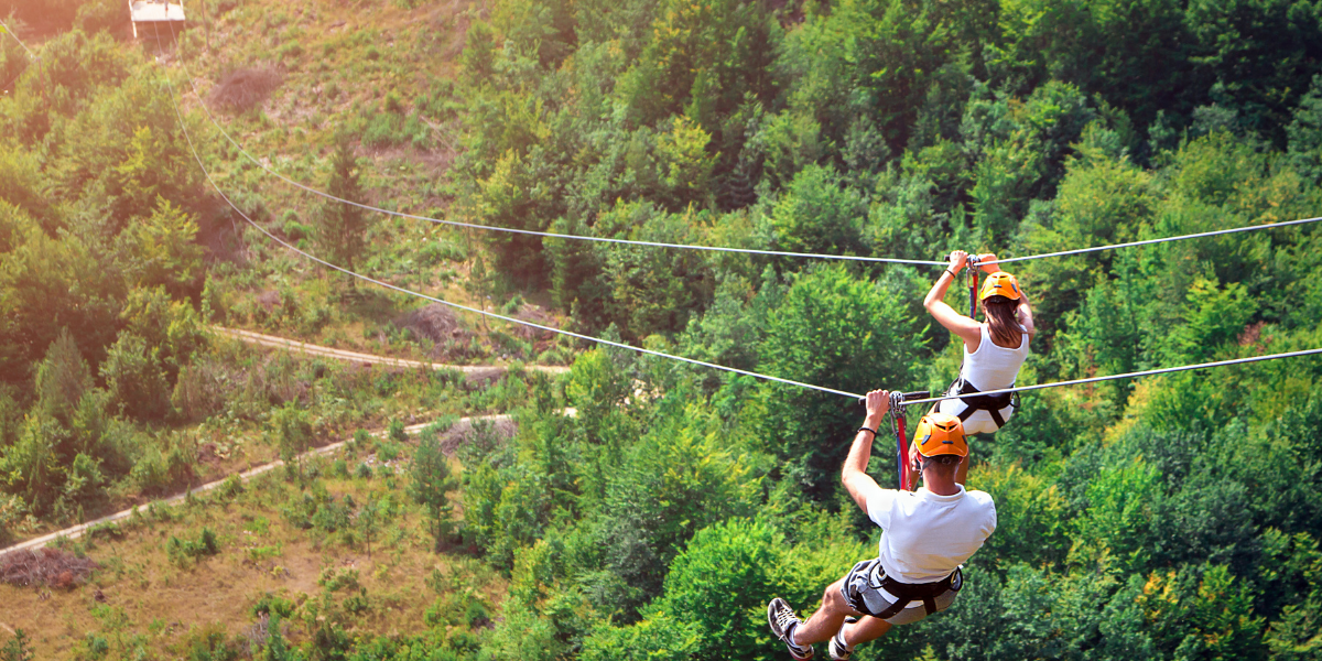 Een deelnemer geniet van een snelle zipline-rit over een schilderachtig landschap als onderdeel van een recreatiepark